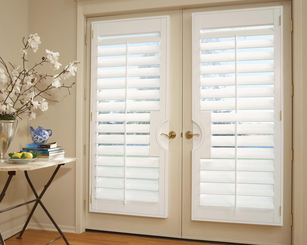 A room with white shutters on the doors and a table