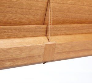 a close up of a engineered bottom rail wooden blind on a window .