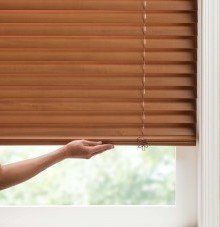 a person is opening a wooden blind using Cordless lift