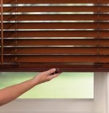 a person is opening a wooden blind on a window, using cordless lift & lock