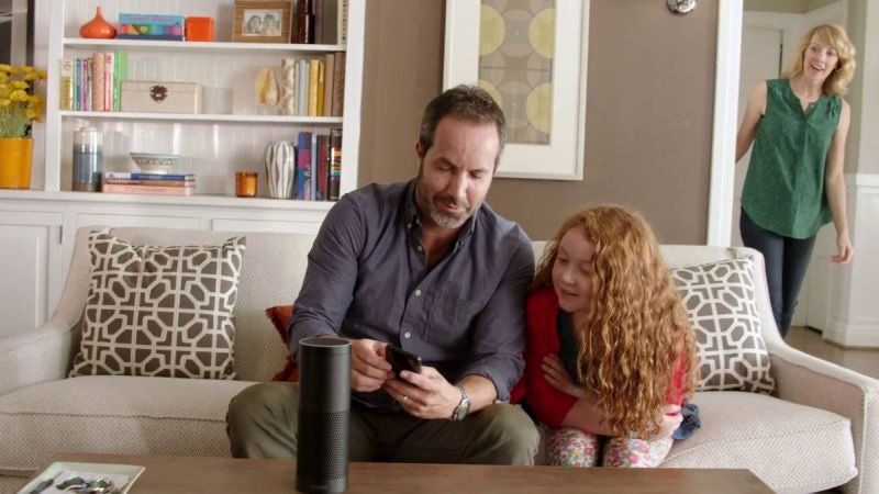 a man and two girls are sitting on a couch looking at a phone