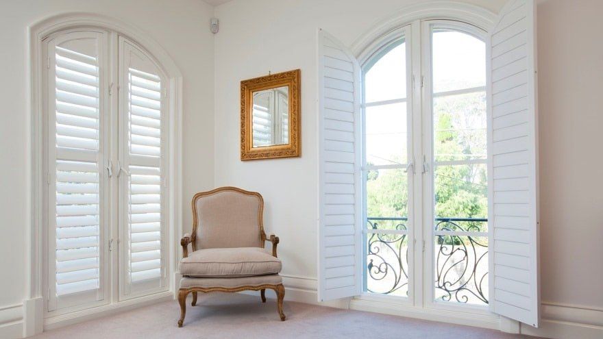 A chair is sitting in the corner of a room next to a window.