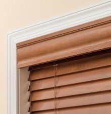 a close up of a optional forte valance wooden blind with a white trim on a window .