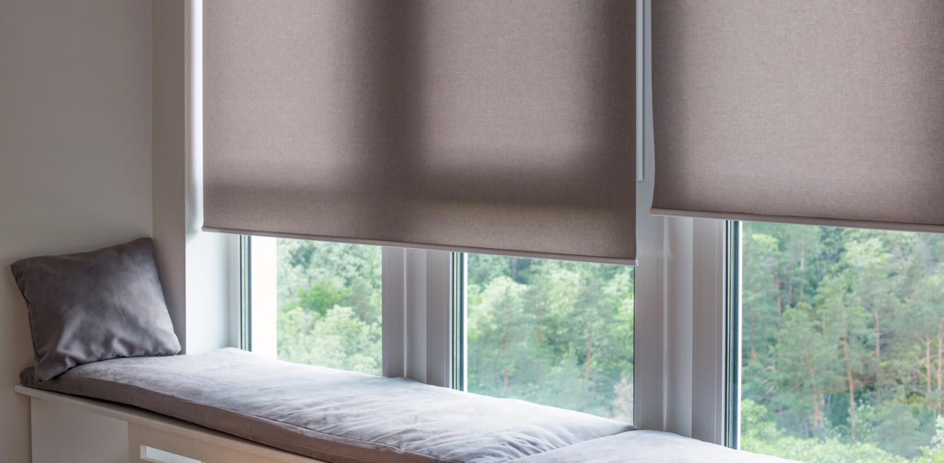 a window seat with a grey motorized window covering