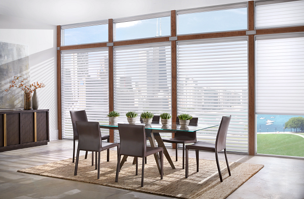 A dining room with a table and chairs in front of a large window.