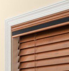 a close up of a wooden tape valance & blind on a window .
