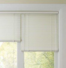a two on one/three on one white blind is hanging on a window in a room .