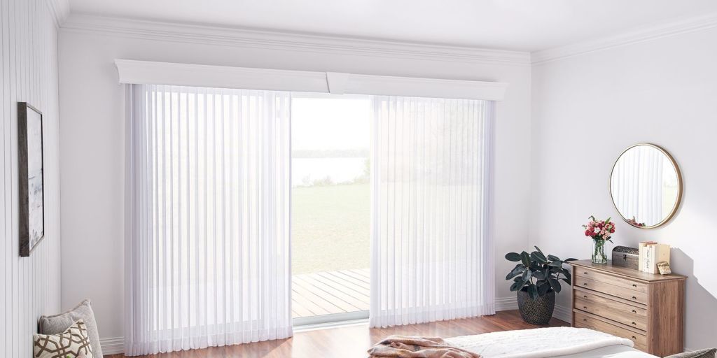 a bedroom with sliding glass doors and white vertical wood blinds