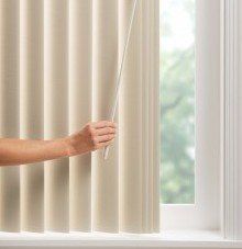 a person is opening a window with vertical blinds using safety wand