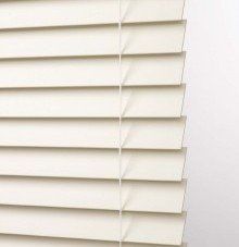 a close up of a routeless slats white blind on a window .