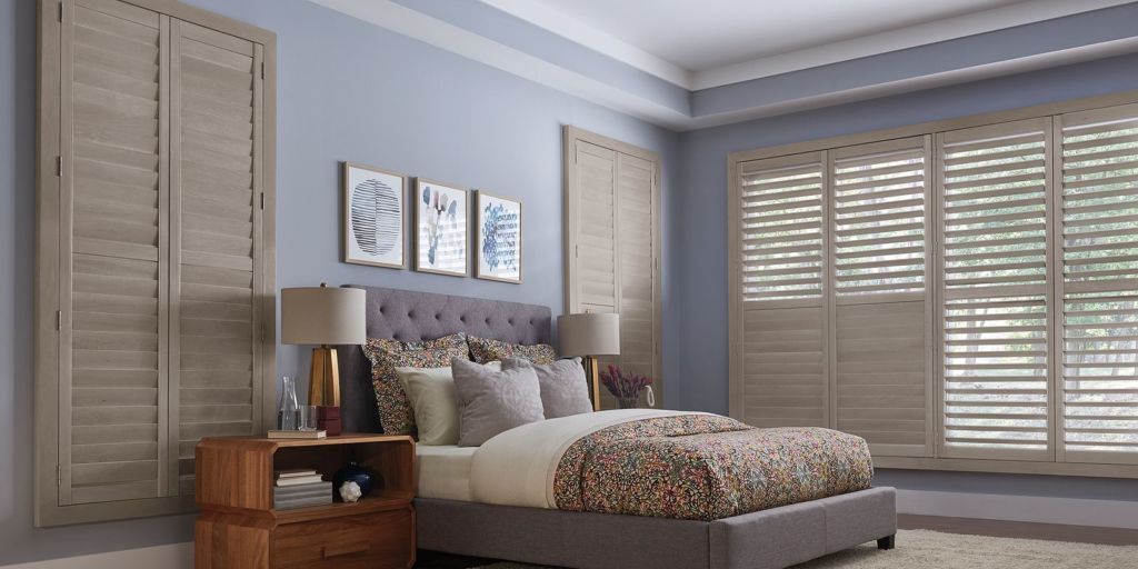 a bedroom with a bed and wood shutters on the windows