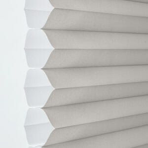 a close up of a white 1 - 1/4 inch single cellular shade on a window .