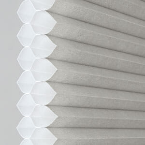 a close up of a white cellular 1/2 double cell blind on a window .