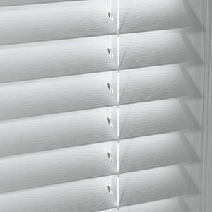 a close up of a white faux wood blind on a window .