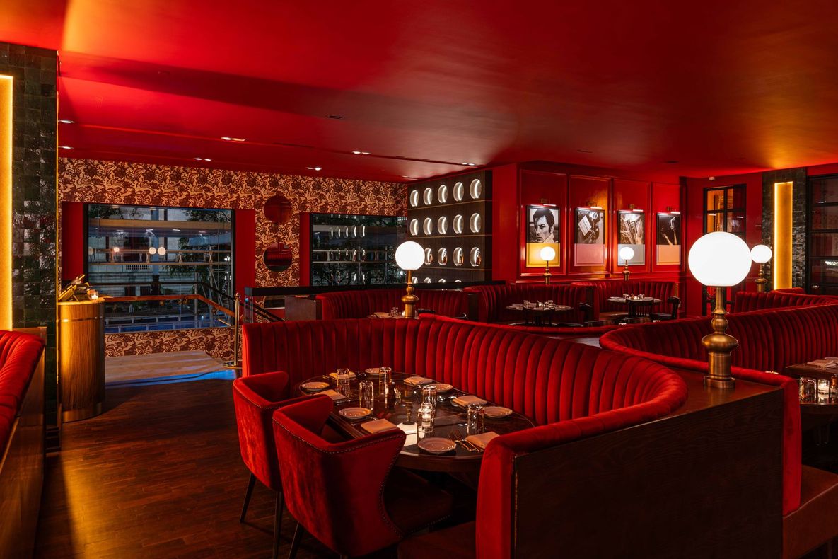 Upscale lounge with velvet booths, tables set for dining, and glowing globe lamps