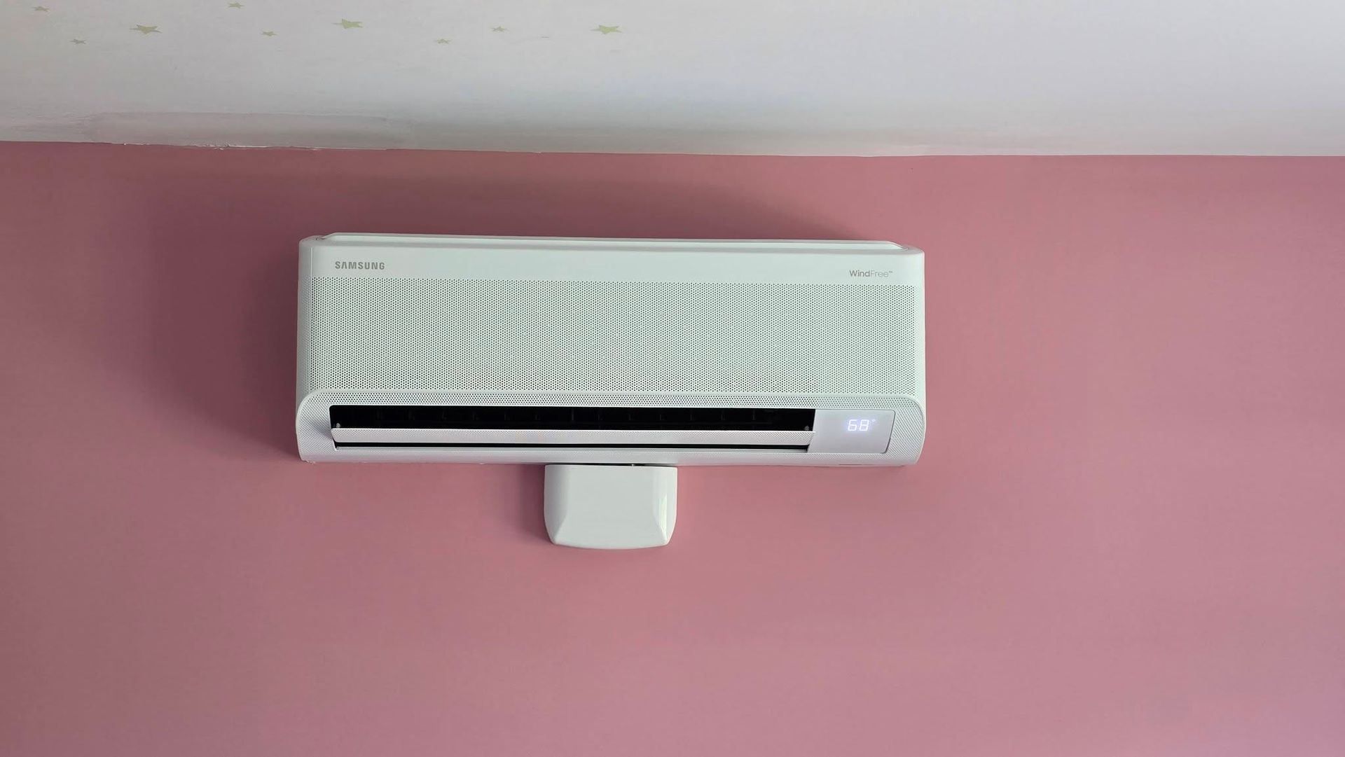 White wall-mounted air conditioner on a pink wall