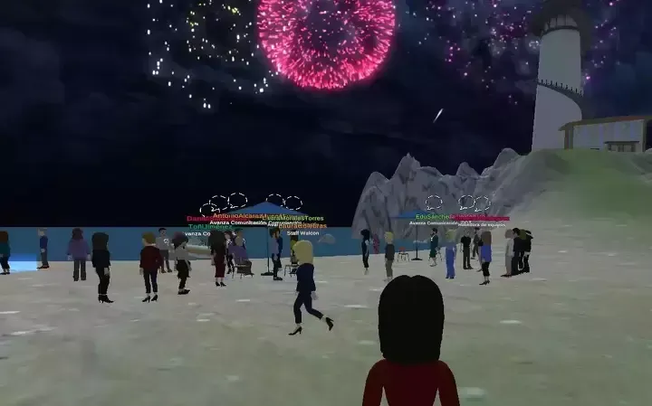 People watch fireworks over the ocean and a small island with a lighthouse.