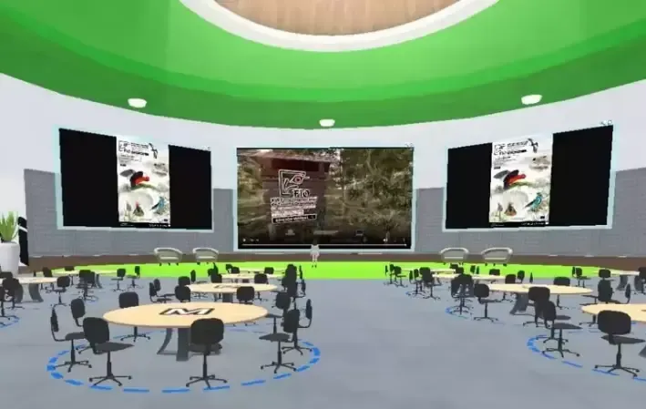 Auditorium with round tables and chairs. Center screen shows video with two posters on either side. Green and gray tones.