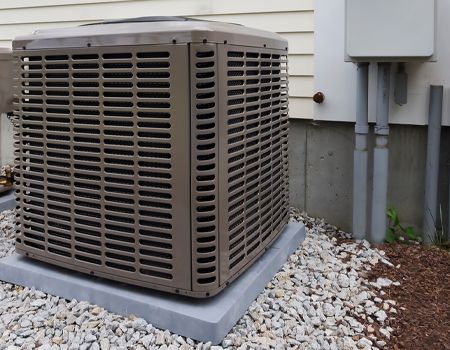 A large air conditioner is sitting outside of a house