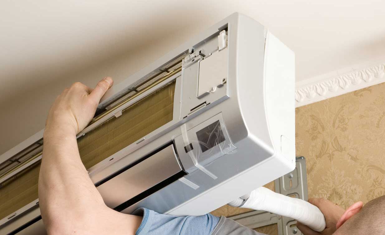 A man wearing red gloves is working on a boiler.