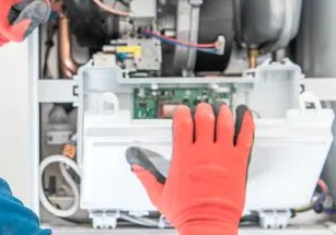 HVAC technician inspecting an appliance, using a headlamp.