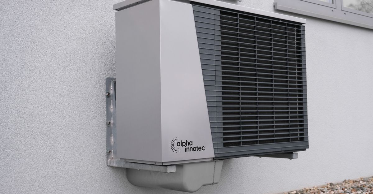 Outdoor heat pump unit beside a home surrounded by standing floodwater