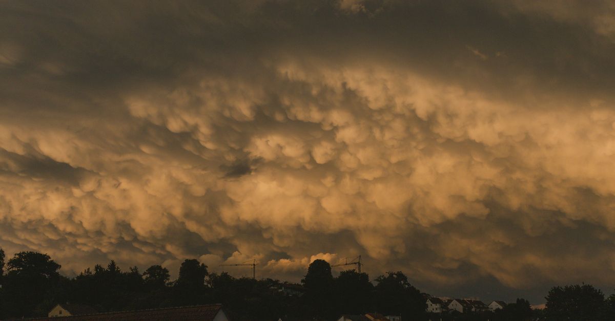 Outdoor air conditioner unit beside a home under dark storm clouds