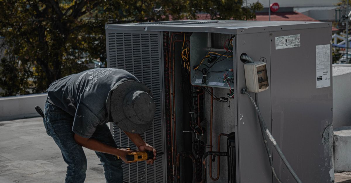 HVAC technician installing a new outdoor heat pump unit beside a home