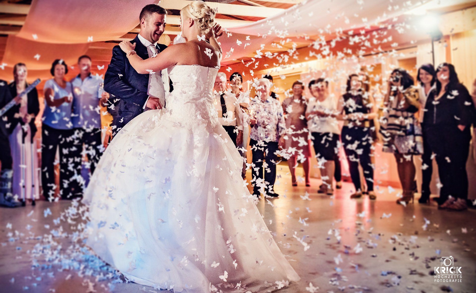 Braut und Bräutigam tanzen unter fallendem Konfetti bei einem Hochzeitsempfang
