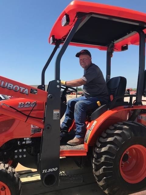 A man is sitting on a kubota tractor