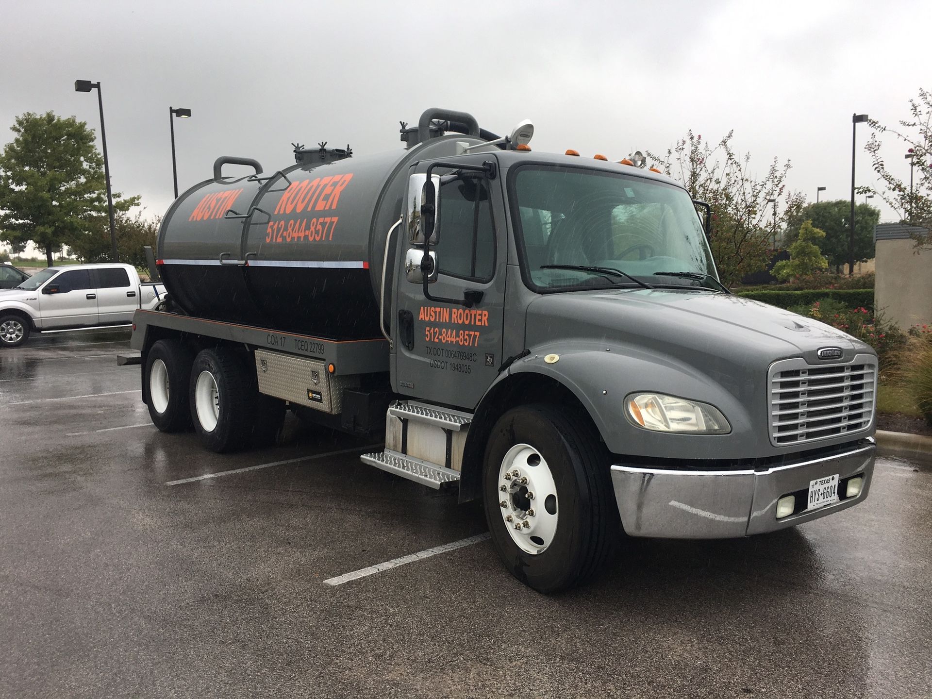 A tanker truck is parked in a parking lot on a cloudy day.tin Roo