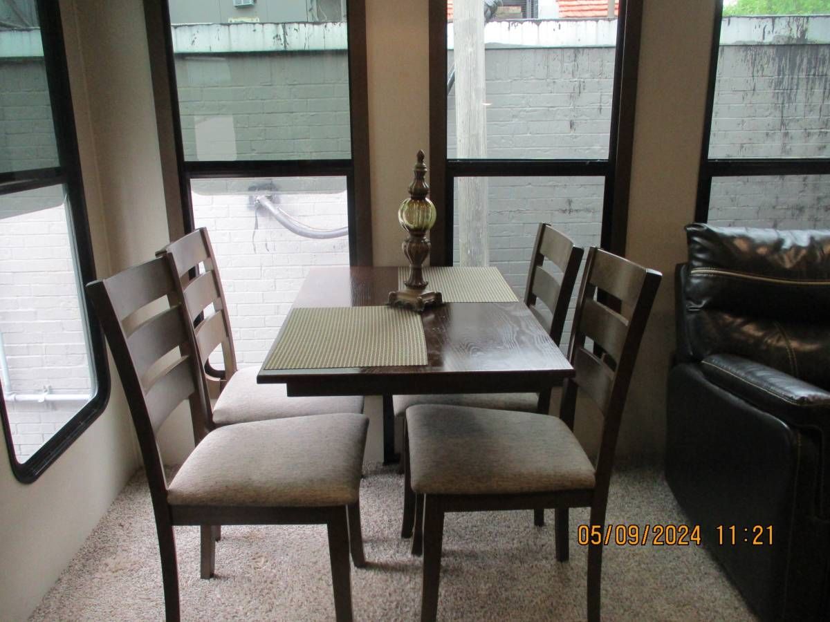 A dining room table with four chairs and a lamp on it