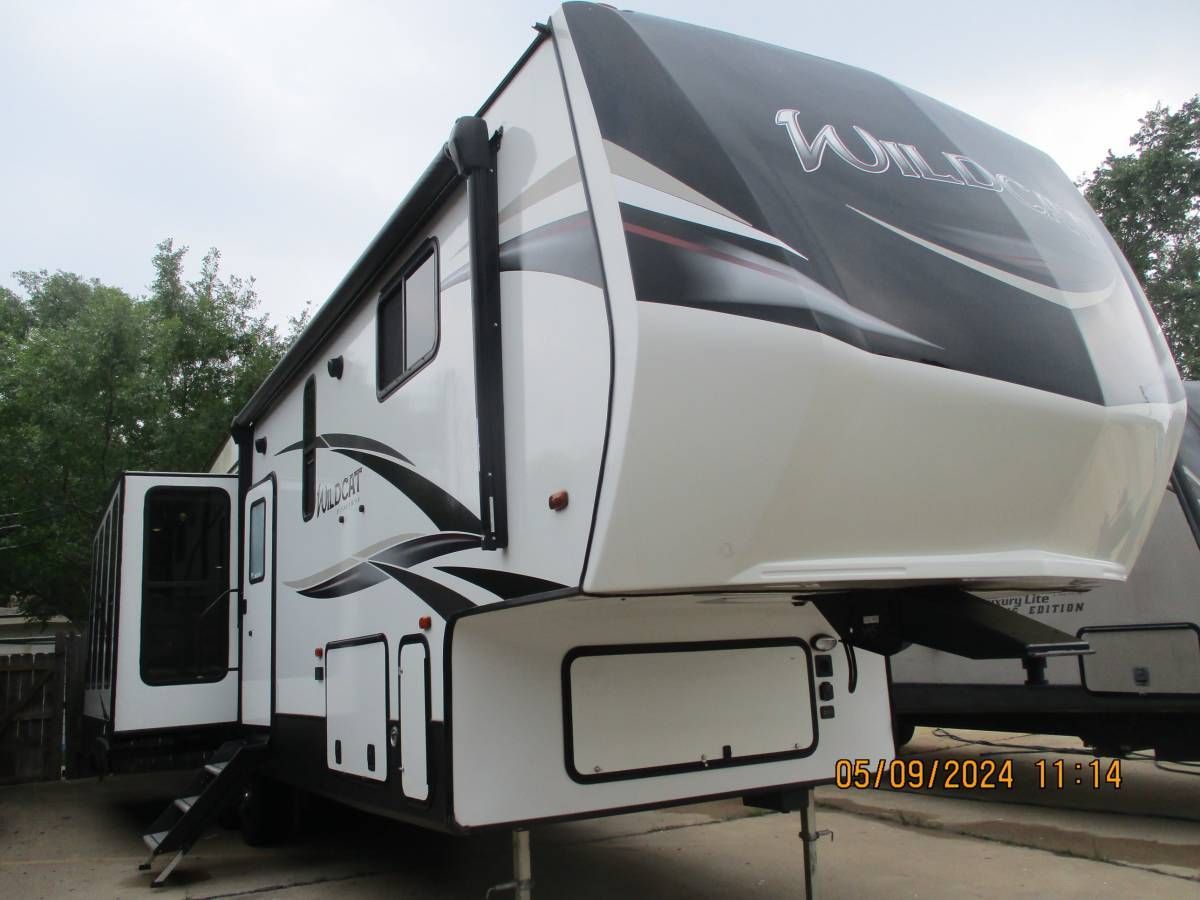A white and black rv is parked in a parking lot.