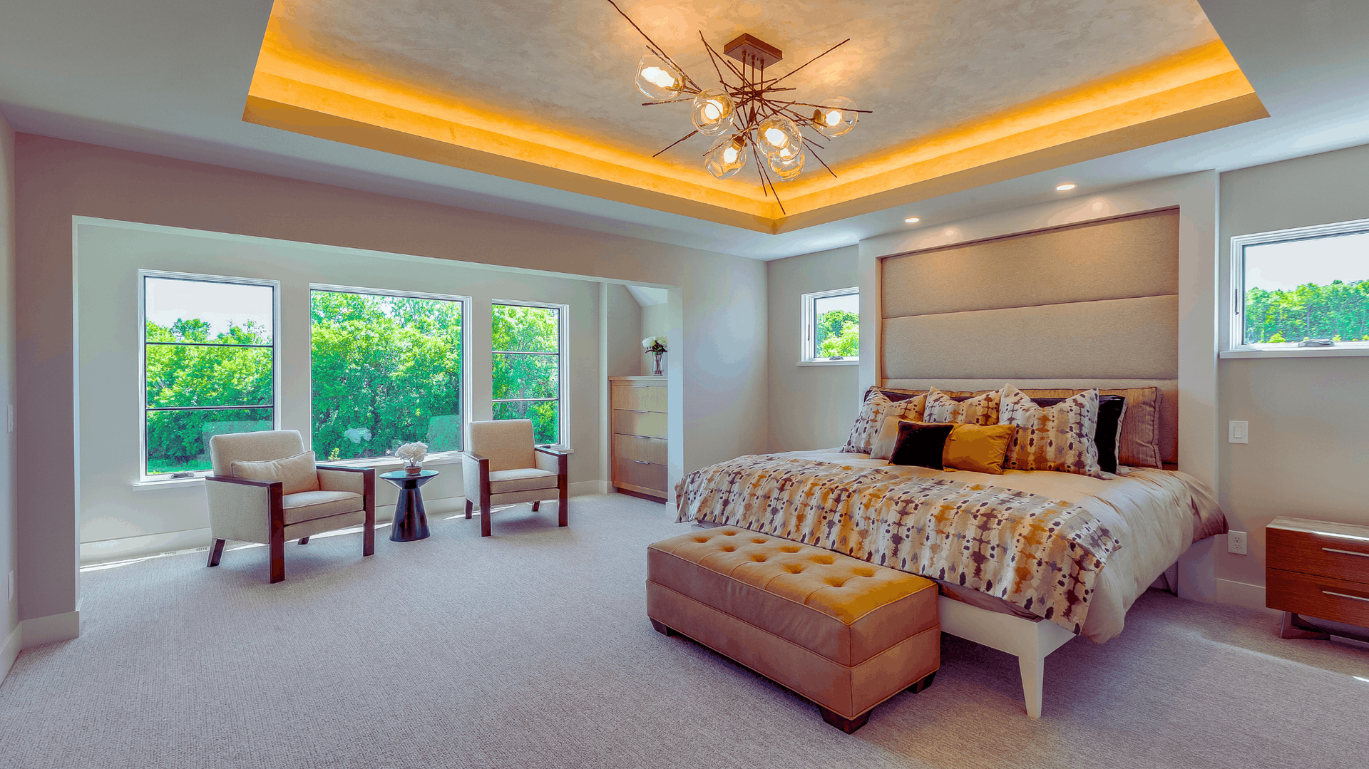 Spacious bedroom with large windows, seating area, large bed, and a decorative ceiling light — Chayser Electrical in Currimundi, QLD