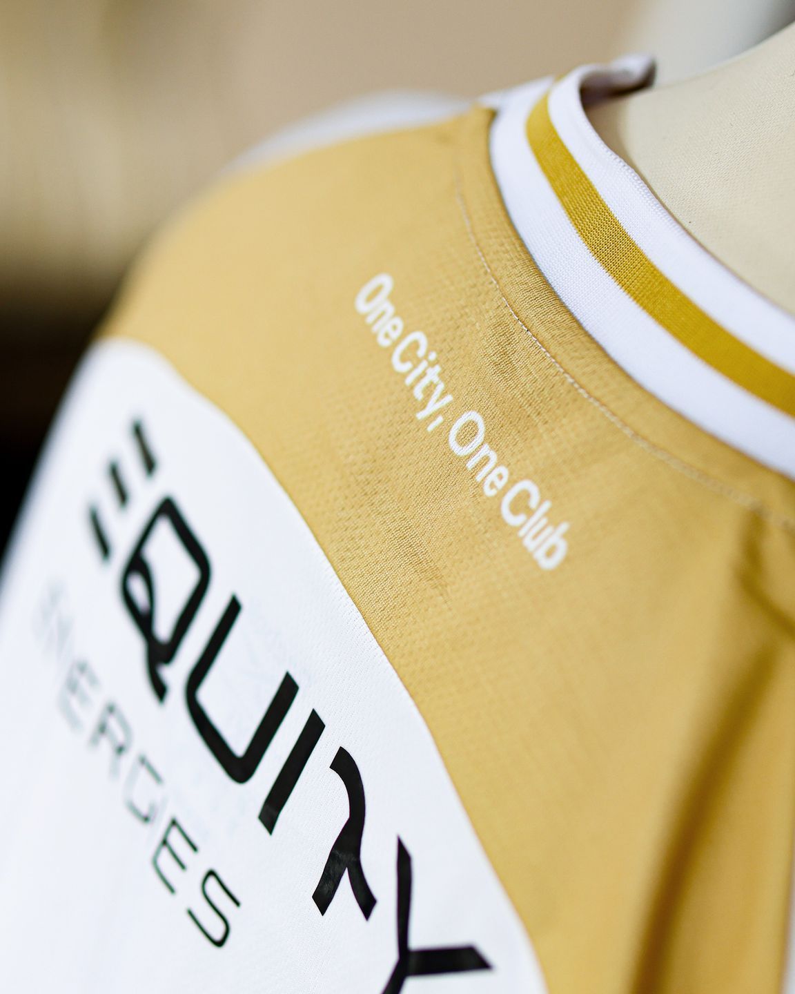 Yellow sports jersey with white trim and sponsor logos reading “OneCity OneClub” and “QUALINX Services”