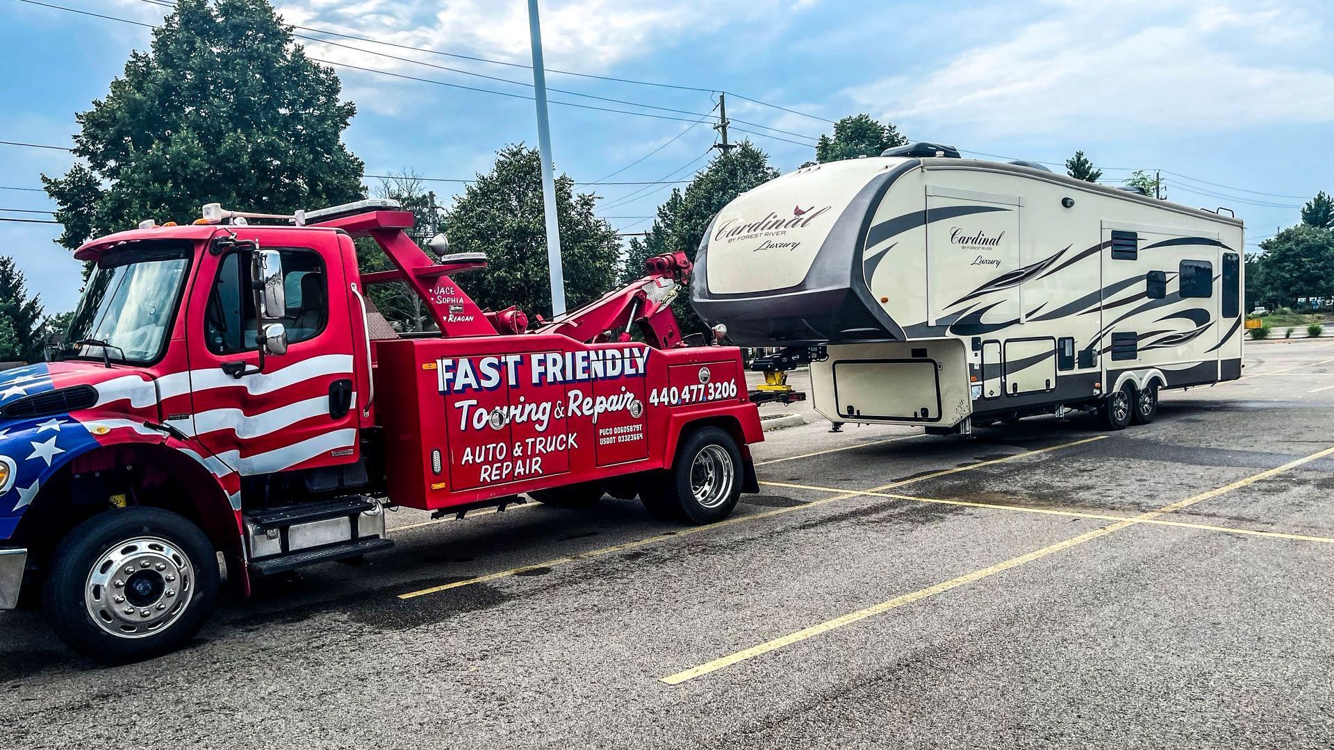 A red and white tow truck is towing a rv in a parking lot.