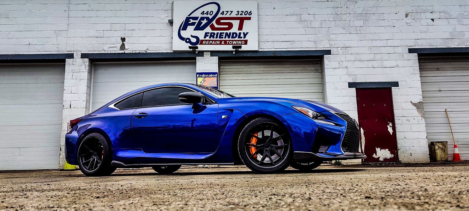 A blue sports car is parked in front of a garage.