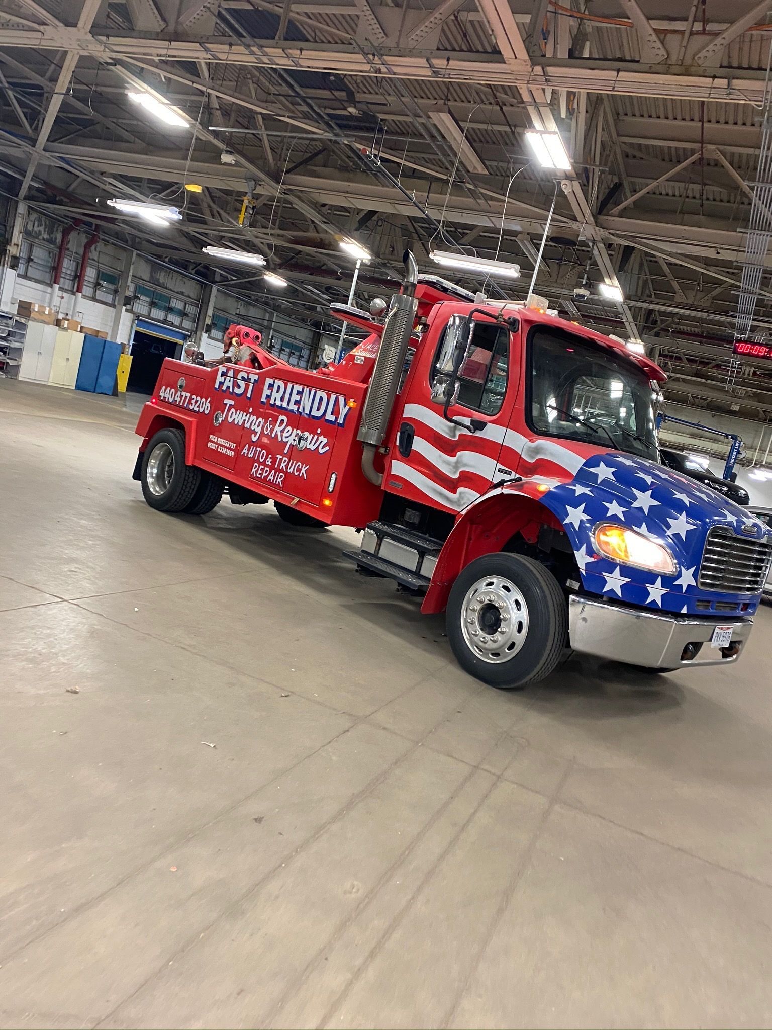 A red and blue tow truck is parked in a warehouse.