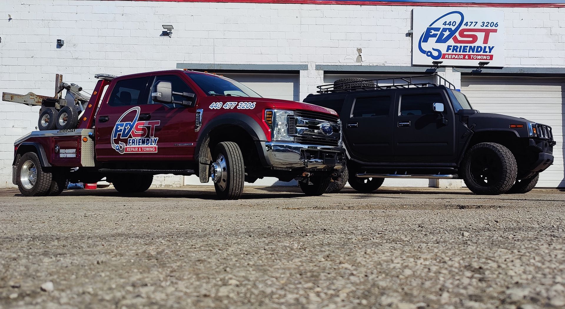 A red tow truck is parked next to a black suv