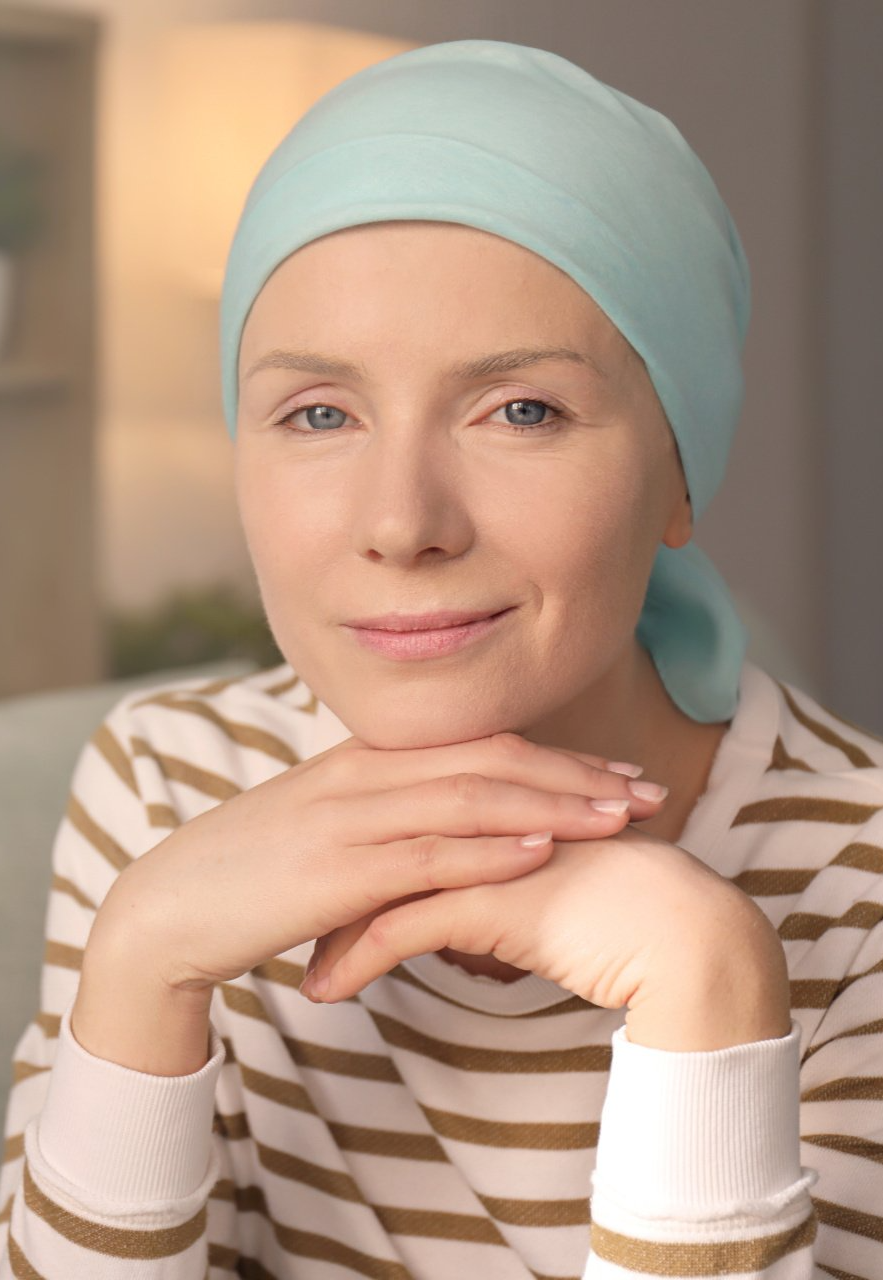 A woman with cancer is wearing a head scarf and a striped shirt.