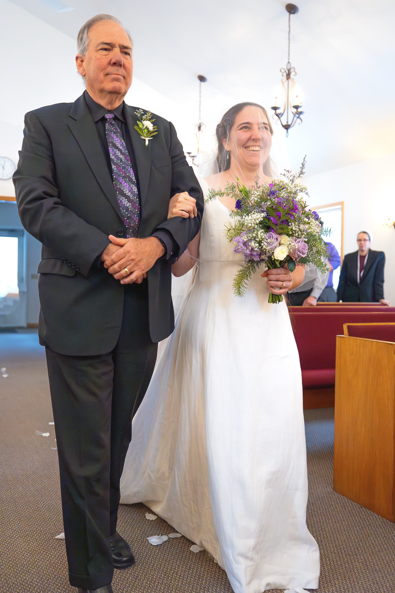 Bride and father of the bride walking down a church aisle