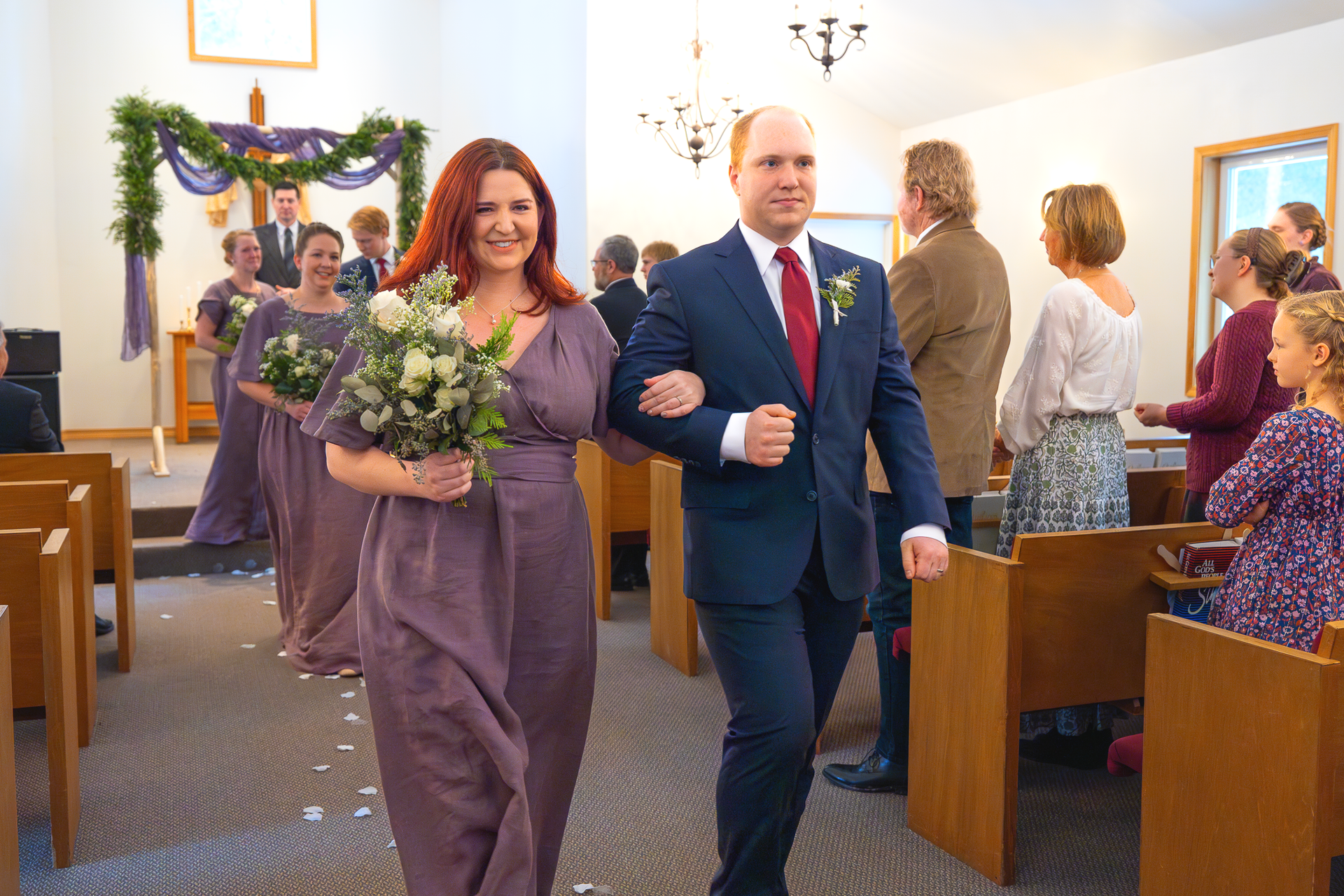 Bridesmaid and groomsmen walking down church aisle