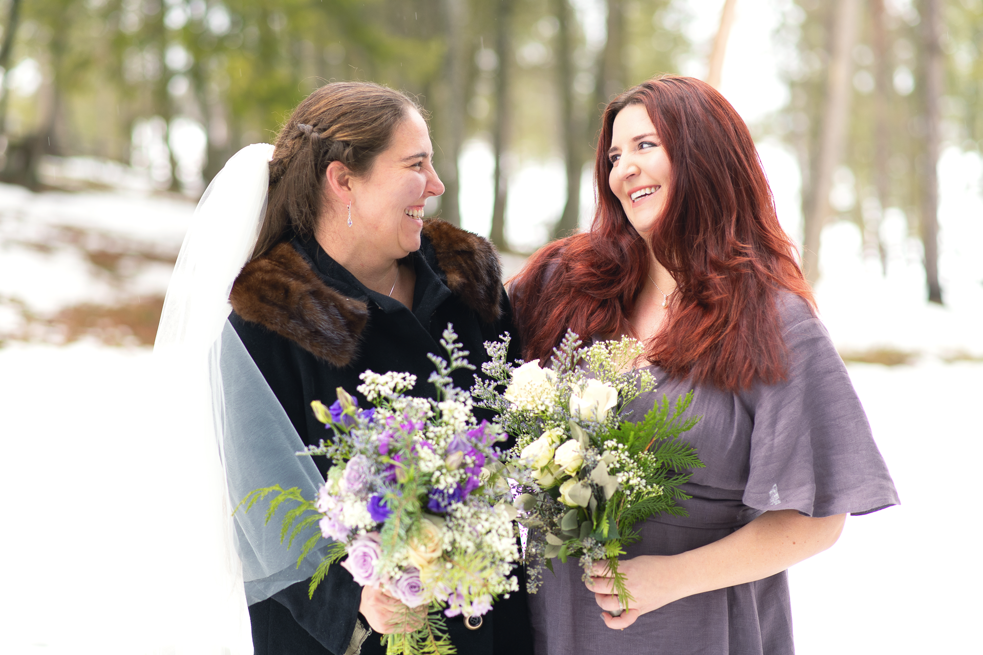 Bride and bridesmaid smiling at each other joyfully