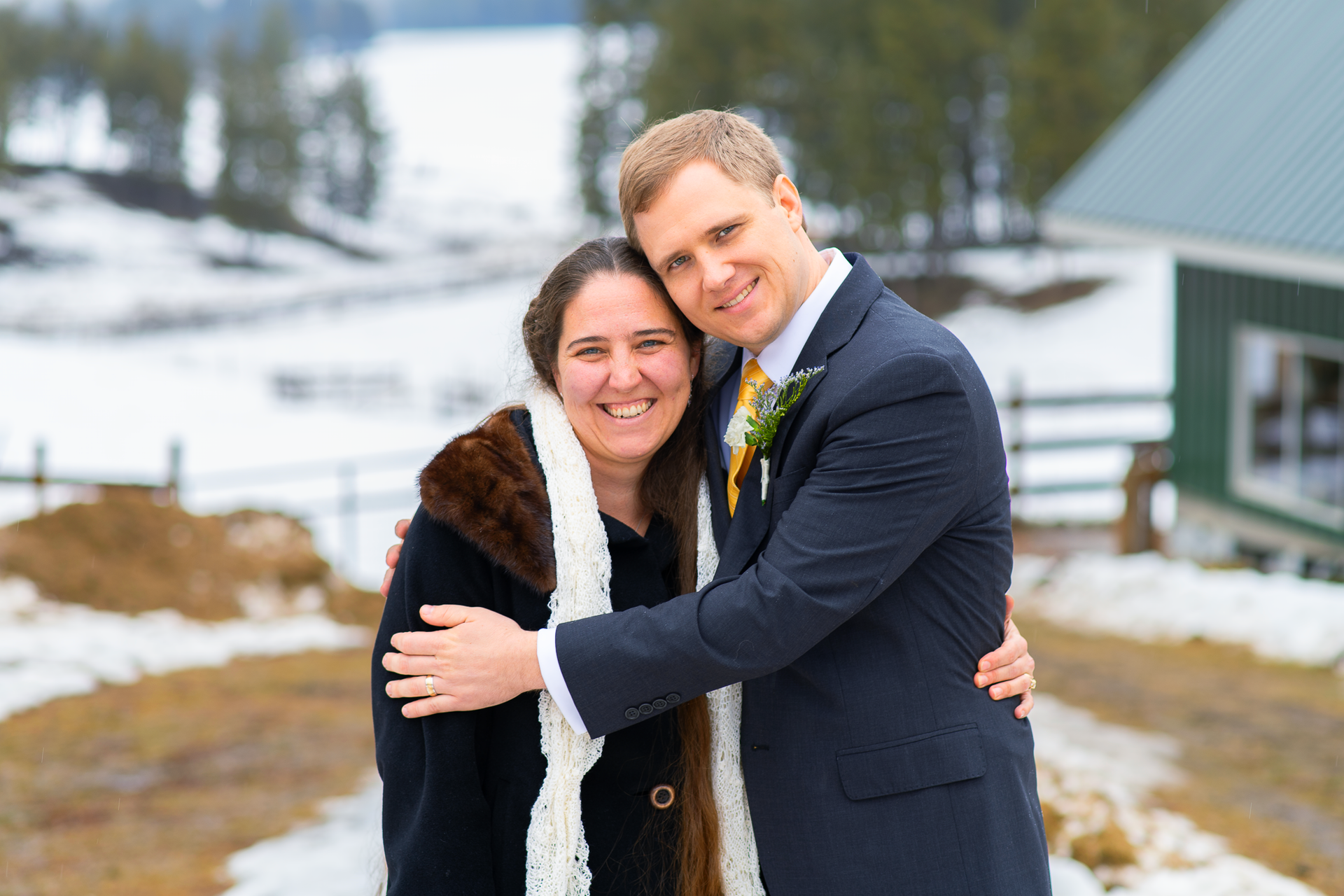 Bride and groom posing for a photo on a snowy farm