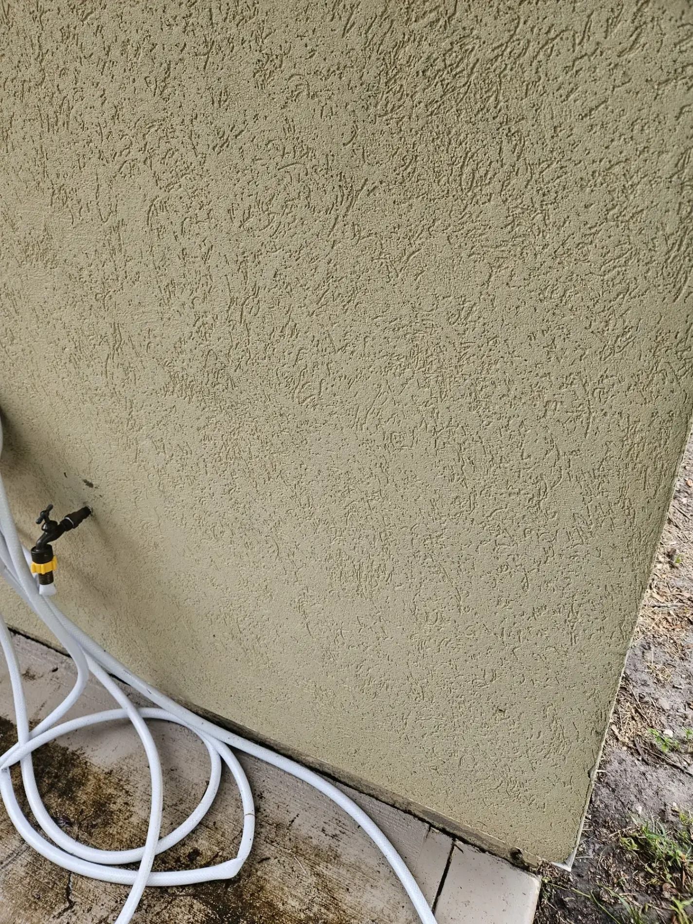 White hose and cords beside a beige stucco wall outdoors