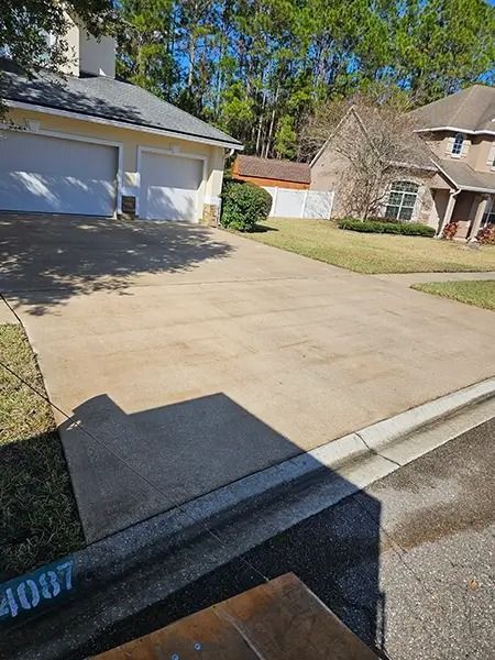 Suburban driveway and garage beside a house, viewed from the curb on a sunny day.
