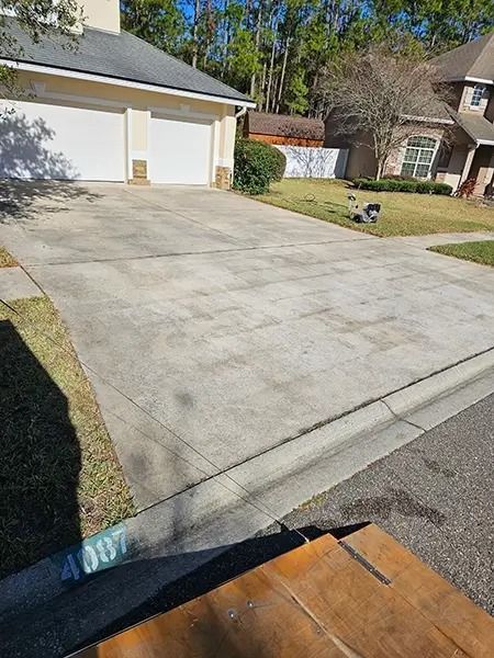 Residential driveway with a two-car garage and a small lawn on a sunny day.