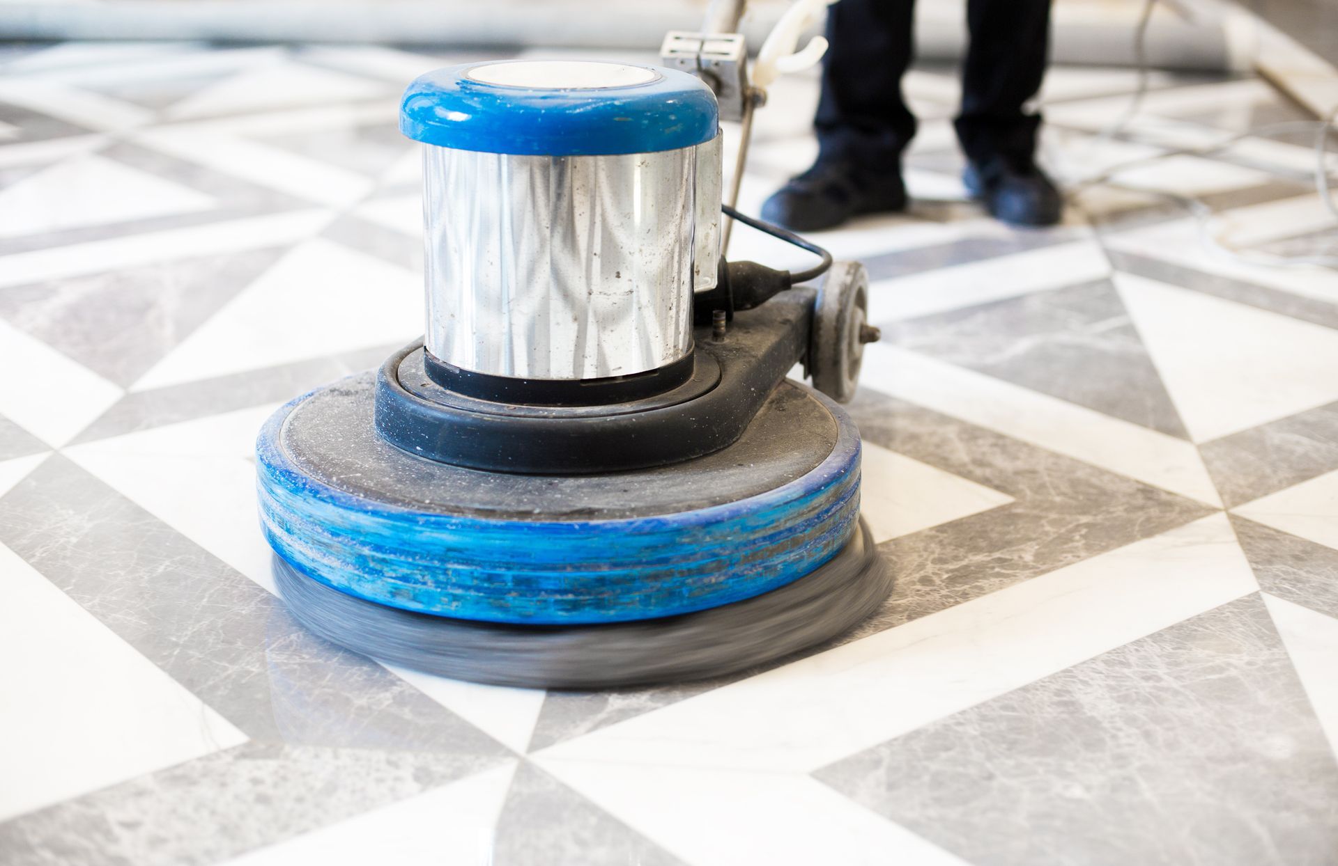 Blue floor-polishing machine on a patterned tile floor in a building hallway