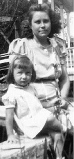 Two people seated outdoors, one standing behind the other, in a black-and-white photo