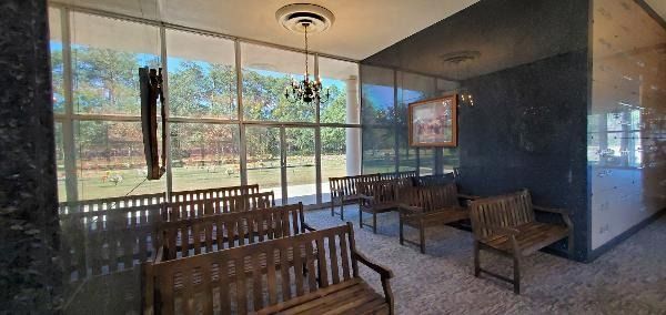 Sunroom lounge with wooden chairs, glass walls, and a small table beside a patio view